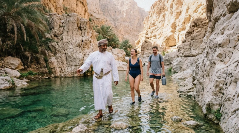 A guide leading two travelers through shallow water between the canyon walls of Wadi Shab